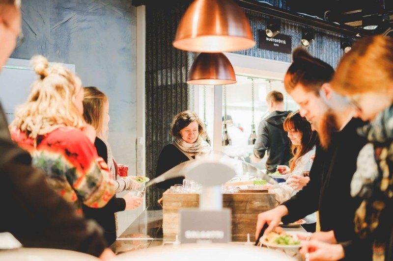 Ravintolan linjastossa ihmisiä ottamassa ruokaa.