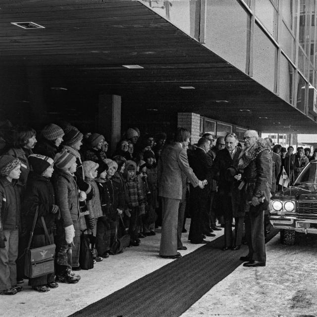 Mustavalkoisessa kuvassa runsaasti ihmisiä ottamassa vastaan presidentti Kekkosta Rentukan edustalla. Maahan on levitetty pitkä matto ja taustalla musta auto.